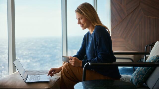 Frau arbeitet am Laptop mit Blick auf das Meer