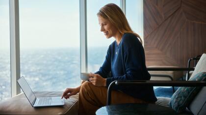 Frau arbeitet am Laptop mit Blick auf das Meer